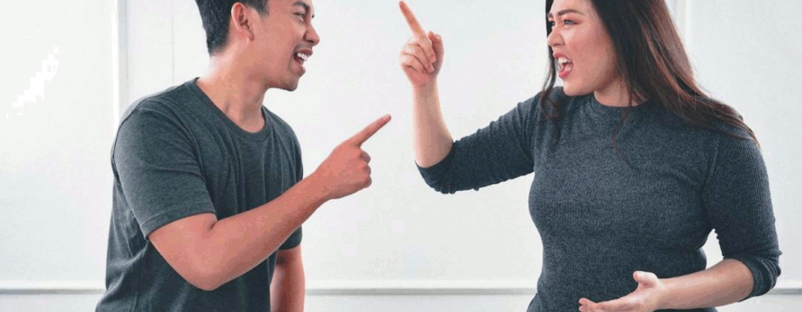 A man on the left and a woman on the right that are pointing at each other while they argue. This photo is used on www.becomingstoic.net in an article called "Retaliation and Anger".