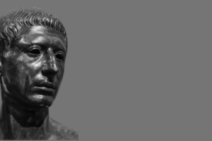 A bust of Cato the Younger is to the left., but it is looking to the right. The background is gray. This is used on www.becomingstoic.net in an article called "Cato the Younger" that is one of the Ancient Sages Serious.